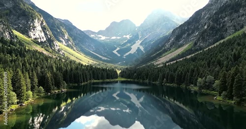 Majestic mountain lake with crystal clear water surrounded by dense forest and rugged peaks, serene nature landscape