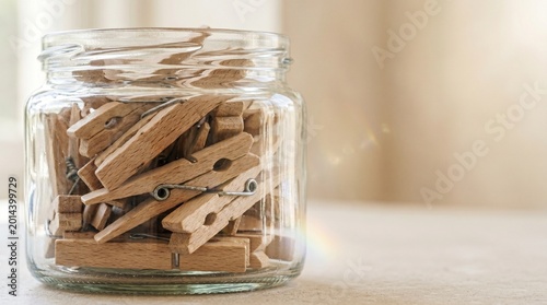 Clothespins arranged in glass jar on wooden countertop  