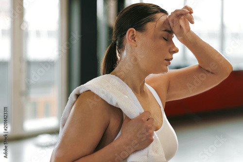 Tableau sur toile Tired woman with sweat on her body and towel after workout in gym