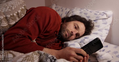 Tired man using a smartphone before sleeping