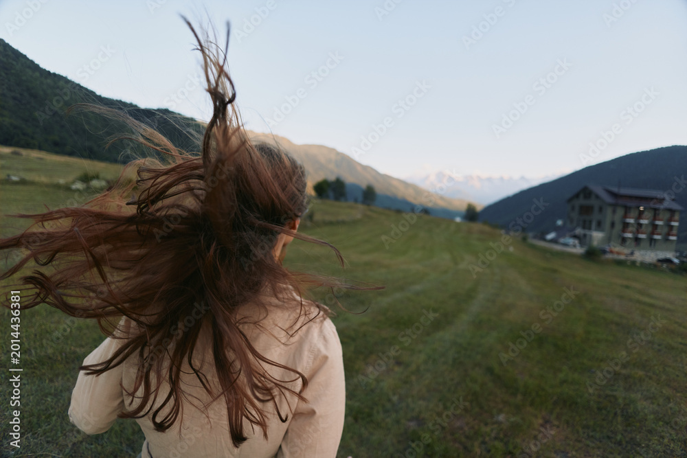 Fototapeta premium A woman lifestyle outdoor countryside field wind hair meadow portrait in a sunlit landscape. A dynamic, carefree moment capturing freedom, exploration, and connection with nature.
