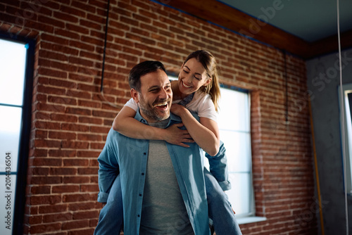 Bild auf Leinwand Carefree couple piggybacking during home renovation process.