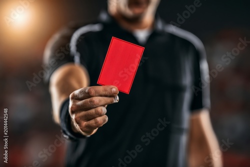 Referee Shows Red Card During Intense Match Moment in Stadium at Night With Fans in the Background