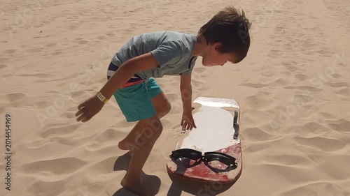 boy finishes sliding down sand dunes in tropical South America gets up and runs back up hill