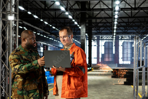 Canvas Print Soldier and factory personnel focused on wartime production within industry plant, machinery and equipment support strategic defense operation