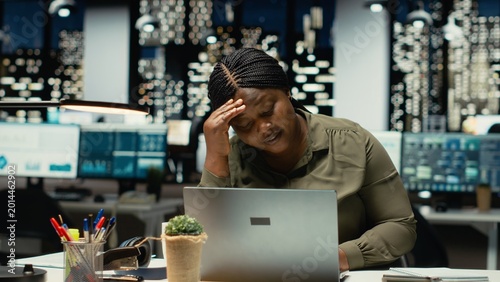 Schilderij op canvas Troubled overworked woman sighing after realizing the late hour, pushing limits at night and dealing with workload alone in office