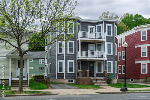 Traditional New England triple decker residential building with updated gray vinyl siding in the Brighton neighborhood of Boston, Massachusetts, USA