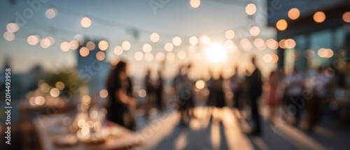 Blurred outdoor event with string lights and people socializing during sunset