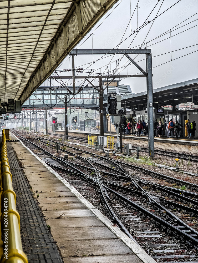 Obraz premium Railway Tracks and Passenger Platforms at Cambridge Train Station Under Overcast Sky in England