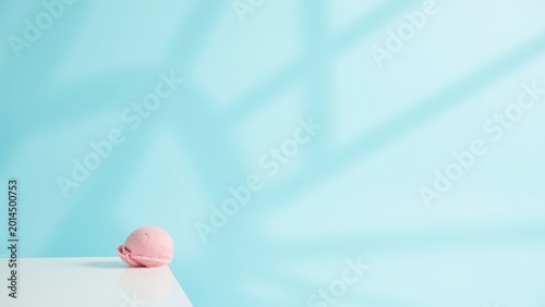 Cake with blue frosting and pink fondant on a white table in front of a window.