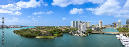 A wide panoramic view of the Tampa city skyline and waterfront harbor with residential buildings, bridges, and boats in Tampa, Florida, United States.