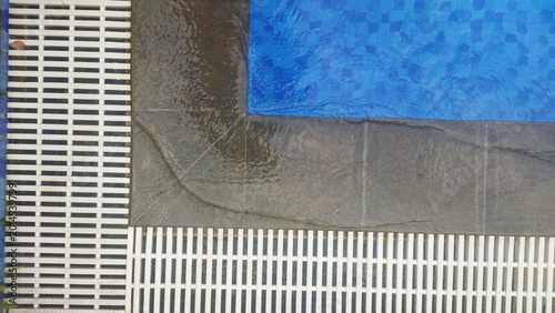 Blue Pool Edge Overlooking Drainage Grate and Concrete Deck