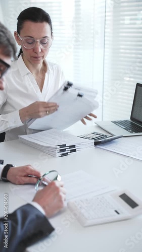 Accountants working together calculating taxes and auditing financial reports in a busy office setting. Audit and taxes in business