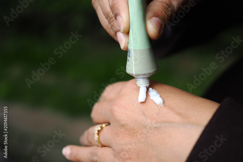 Applying cream to the hand in a garden setting