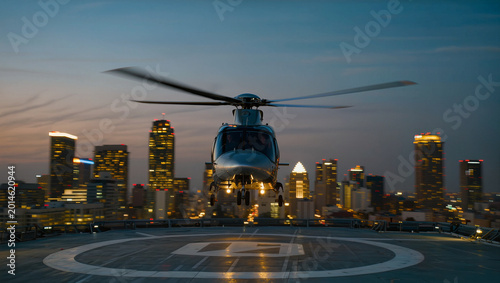 Quadro em tela Helicopter landing on a helipad in a city at dusk with skyscrapers in the backgr
