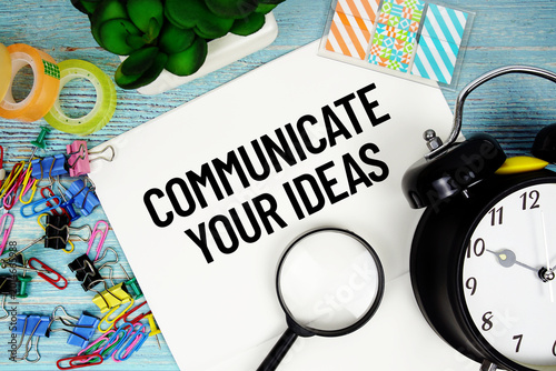Foto Communicate Your Ideas text on a paper surrounded by office supplies, a magnifyi
