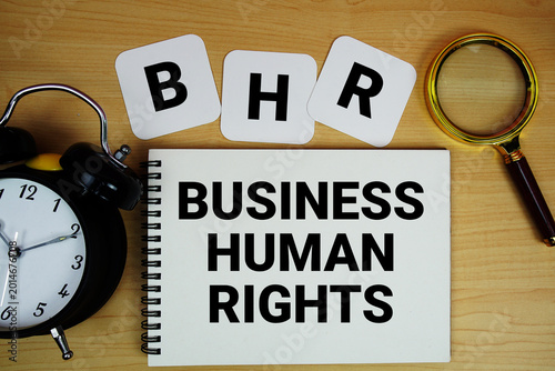 BHR Business Human Rights text written on notepad with magnifying glass and alarm clock on wooden background