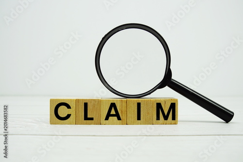 Photos CLAIM alphabet letters with magnifying glass on wooden background