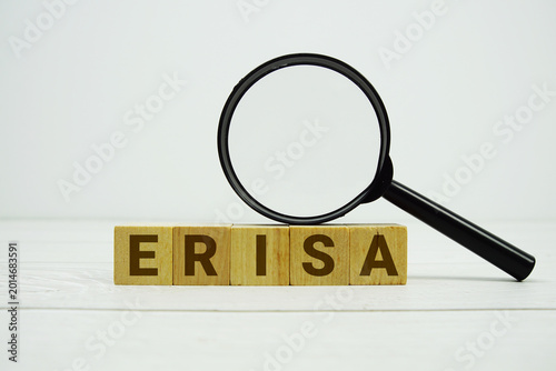 ERISA Employee Retirement Income Security Act alphabet letters with magnifying glass on wooden background