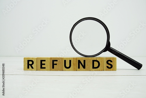 Foto REFUNDS alphabet letters with magnifying glass on wooden background