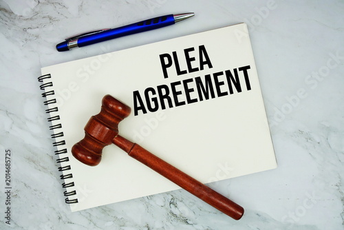PLEA Agreement text written on notepad with pen and judge gavel on marble background