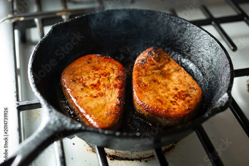 A view of some mushroom steaks, in a cast iron skillet.