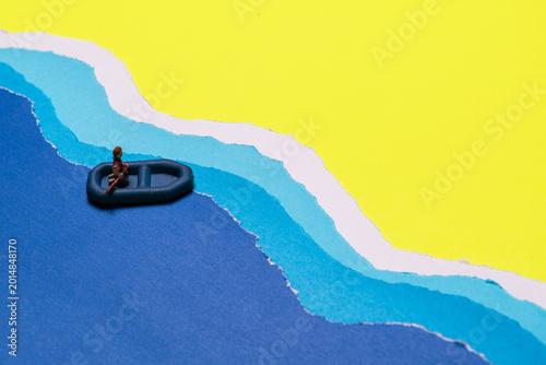 Photos Miniature Person Seated In Small Dinghy Boat Floating On Blue Wavy Water Against