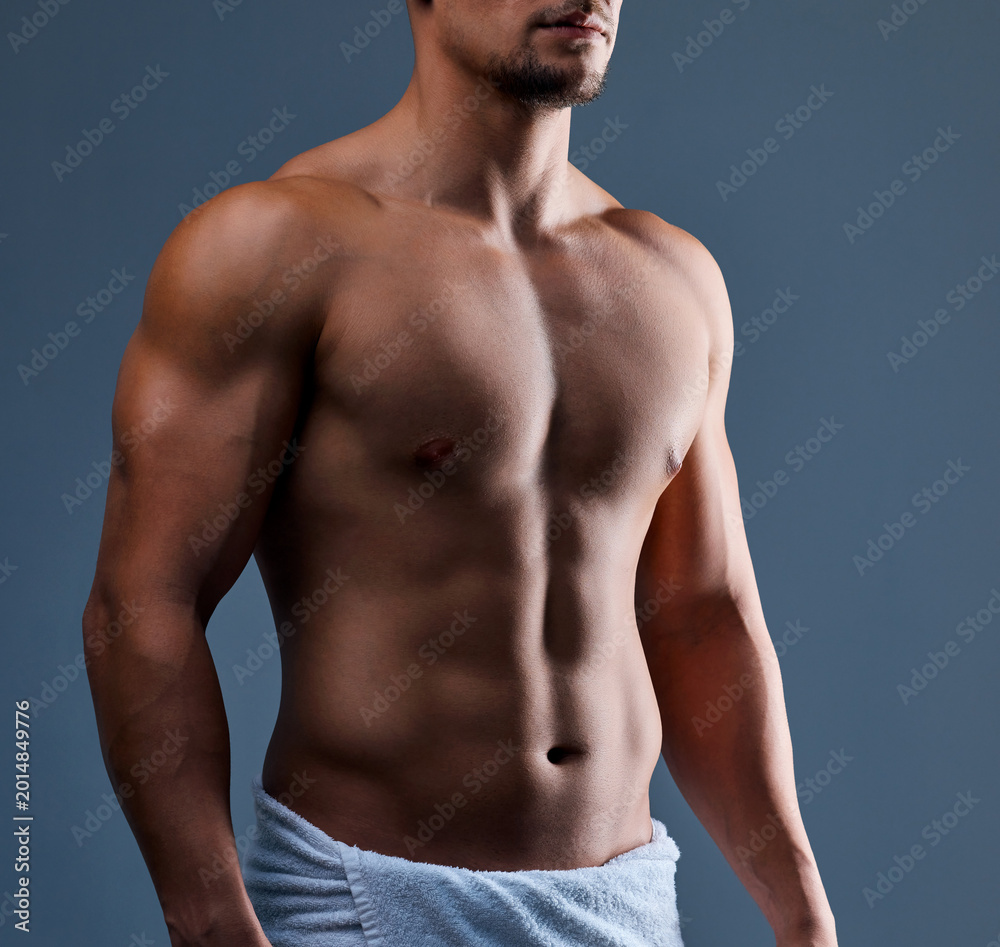 Obraz premium Abs, towel and man in studio for fitness, body care and core muscle development on background. Bodybuilder, athletic person and strong chest with six pack growth, stomach and health for wellness