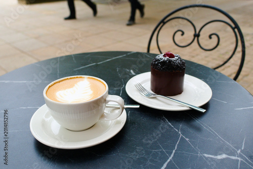 Cappuccino and cake in Warsaw. At a table outside the cafe.