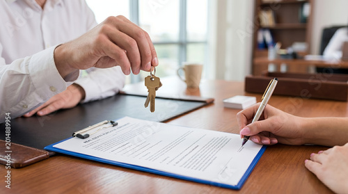 Businessman handing over keys signing agreement in office space
