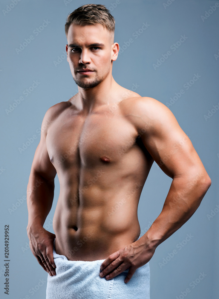 Obraz premium Serious, athlete and man with body in studio for fitness, strong muscle or transformation progress. Portrait, person or towel with muscular torso, bicep strength and sports results on gray background