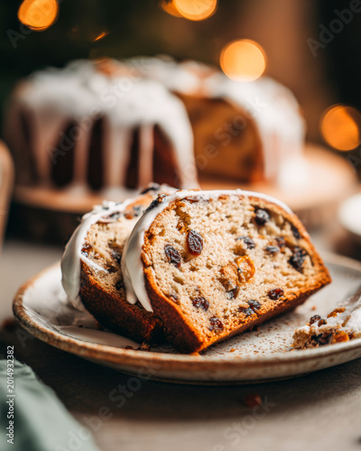 Close-up of festive sweet bread with icing and raisins served on a plate in warm light