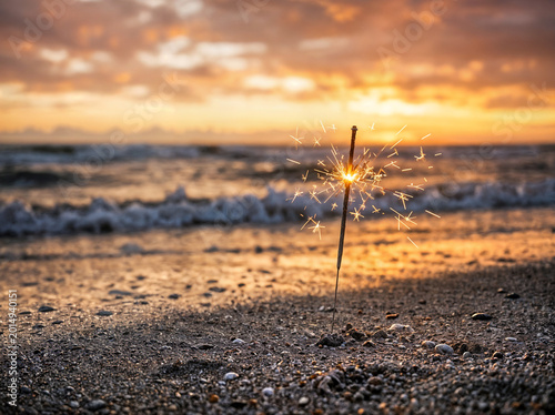 sparkler glowing on beach at golden hour