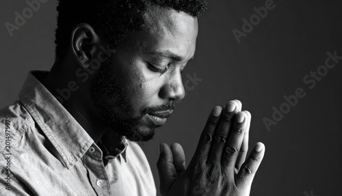 A contemplative person with closed eyes and clasped hands, appearing to be in deep thought or prayer