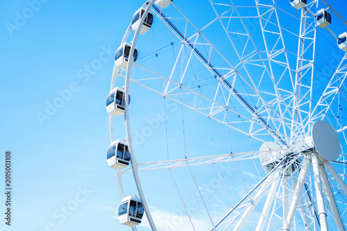 Foto A large white Ferris wheel with modern enclosed gondolas set against a vibrant, clear blue sky