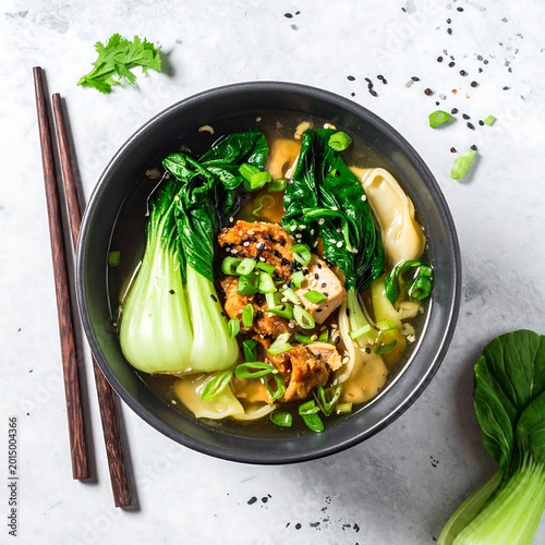 Steaming bowl of Asian-inspired dumpling soup with greens