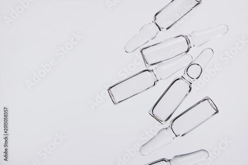 Transparent glass ampoules arranged on light background, representing medical research and healthcare