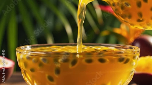 Tropical passion fruit juice pouring into glass bowl, fresh exotic yellow nectar with seeds, organic summer beverage in lush garden