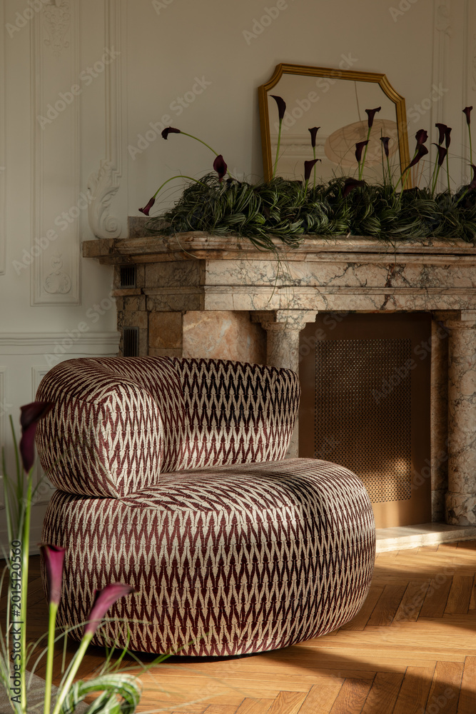 Fototapeta premium Elegant Living Space with Modern Armchair and Marble Fireplace Adorned with Dark Calla Lilies and Gold Mirror