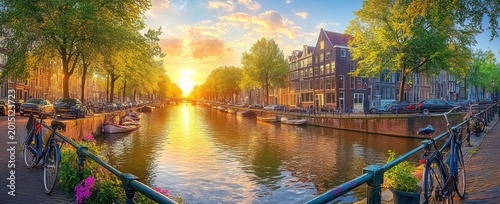Sunset over a tranquil urban canal with bicycles on a bridge, moored boats, tree-lined streets, historic row houses and golden reflections on the water