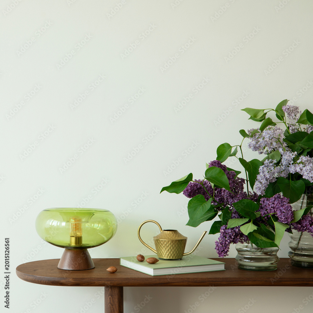 Fototapeta premium A serene interior with a modern green lamp, watering can, and fresh purple flowers on a wooden console table