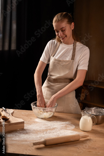 Happy woman kneading dough in the kitchen, enjoying baking fresh bread or pastry from scratch