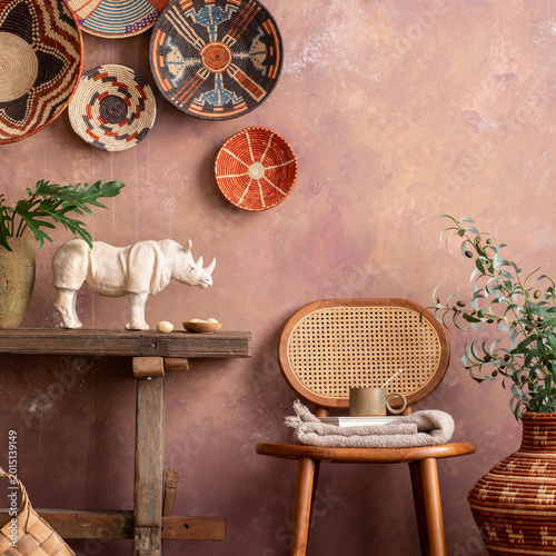 Photography The stylish ethnic compostion at living room interior with wicker baskets, wooden bench, rattan chair and elegant personal accessories