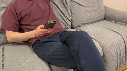 ソファーでスマホを操作する男性