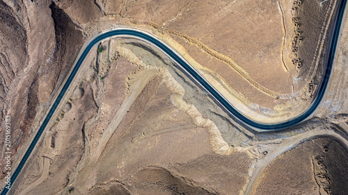 Konstfotografi Top view aerial drone shot of winding S-curve mountain road through arid desert