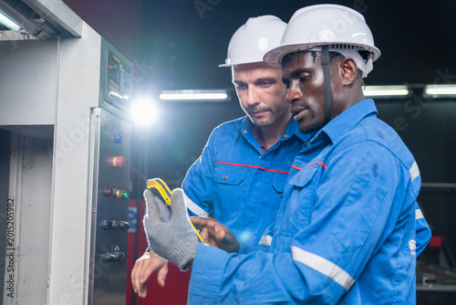 Industrial workers collaborating on equipment maintenance in factory technical inspection indoor professional setting