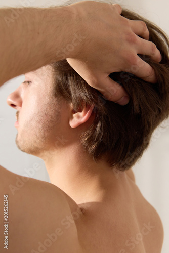 A man touches his long hair. Real life photography
