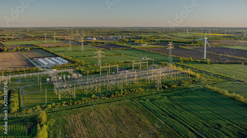 фотографія Electrical substation with large-scale battery energy storage system (BESS) installation, power lines, and wind turbines in the background