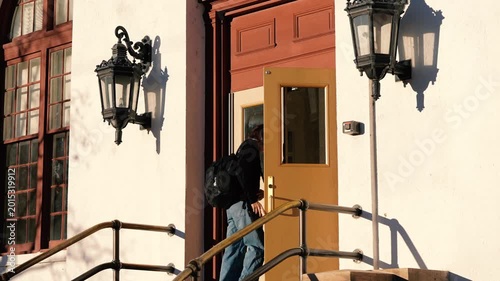 Young Man Walks Through Door of Building