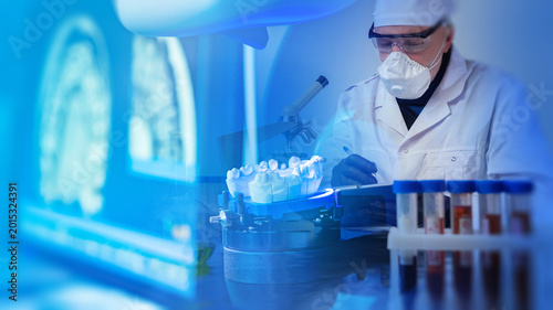 Fotografia Dental laboratory, technician studies jaw model and medical samples with microsc